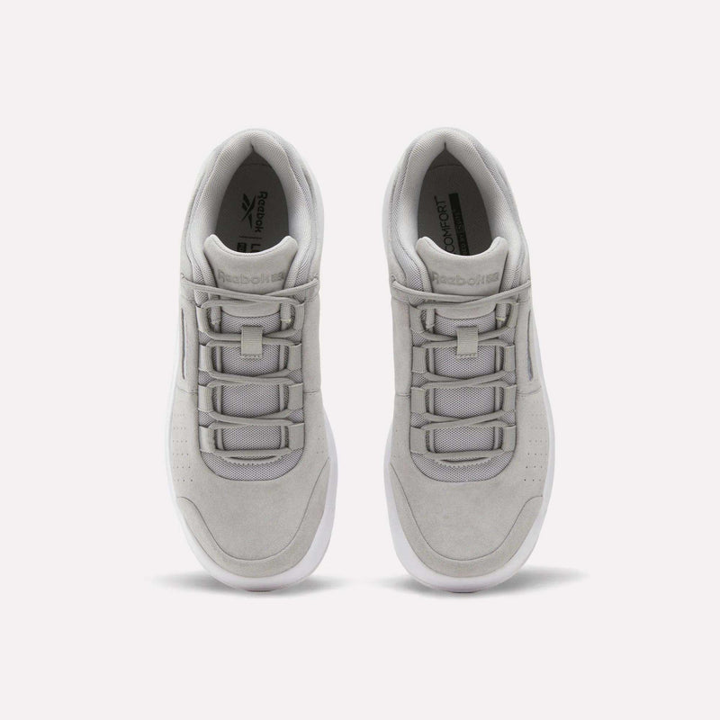 A top view of a pair of Reebok DMX Comfort+ Classic walking shoes in light gray, featuring white soles and distinctive wide lace loops with Dynamic air cushioning, placed side by side on a plain white background.