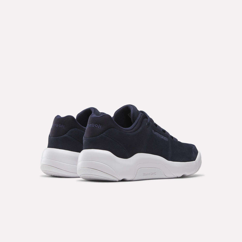 A pair of Reebok DMX Comfort+ Classic walking shoes in navy blue with white soles, made from premium leather, displayed from the back and side on a light background.