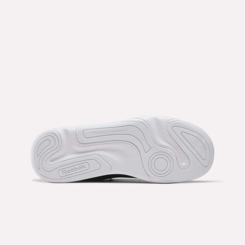 The image displays the white, textured outsole of the Reebok DMX Comfort+ Classic walking shoe, featuring circular and wavy grip patterns along with the Reebok logo near the heel—details that complement its premium leather upper.