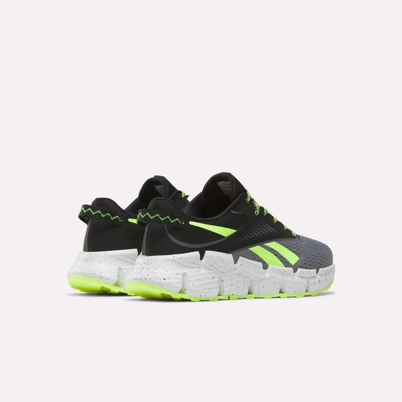 The Reebok Zig Dynamica 6 Running Shoes for big kids feature black and gray uppers with neon green accents, zigzag details, and thick white speckled soles with Zig technology and neon green outsoles, shown on a plain white background.