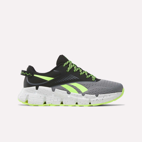 The Reebok Zig Dynamica 6 Running Shoes for big kids in Grey 4/Black/Digital Lime feature neon laces, black detailing, and a chunky speckled sole—engineered with Zig technology for superior running performance.