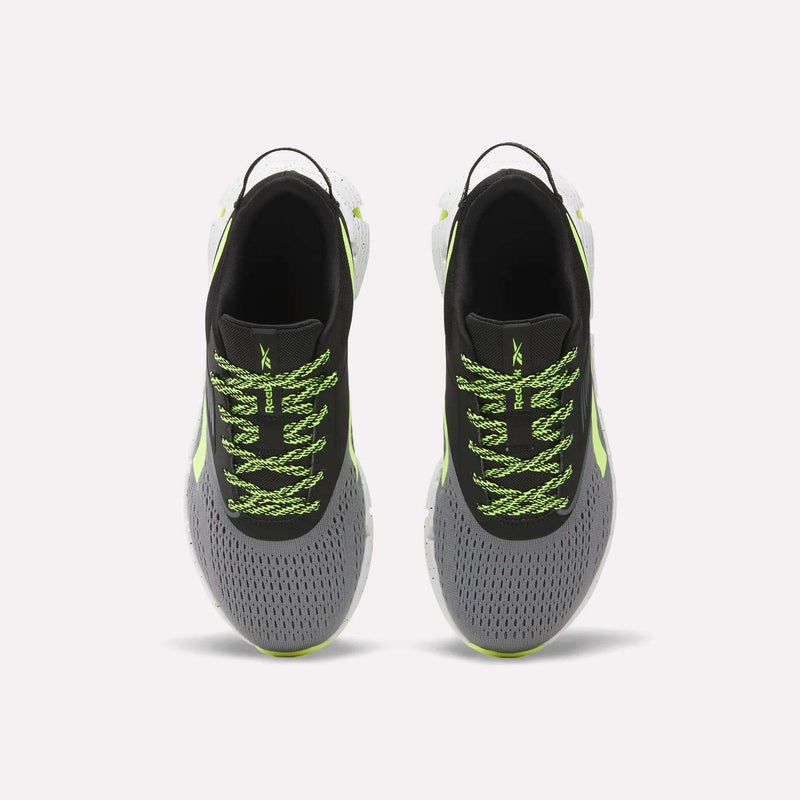 A pair of Reebok Zig Dynamica 6 Running Shoes for big kids, in gray with black interiors, neon green patterned laces, Zig technology soles, and light green accents, displayed from above on a plain white background.