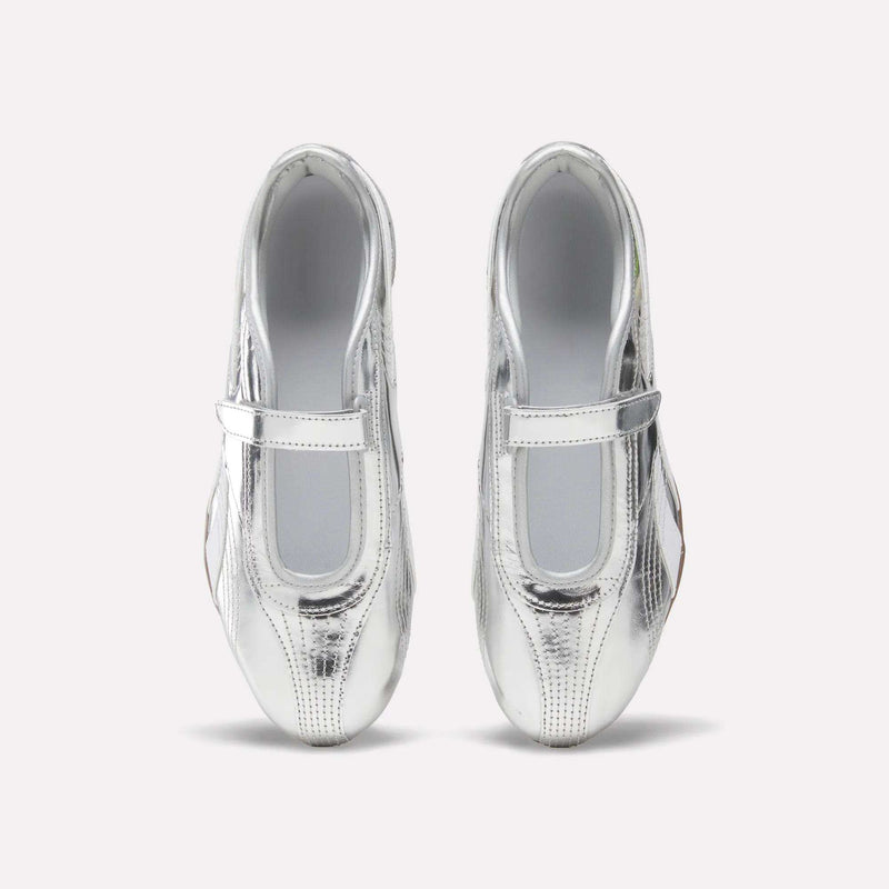 Top view of a pair of Women’s Ultra Lo Mary Jane Shoes by Reebok in shiny silver, featuring a single strap across each shoe and displayed on a plain light background. These stylish, low-profile Reebok shoes provide both elegance and comfort for any occasion.