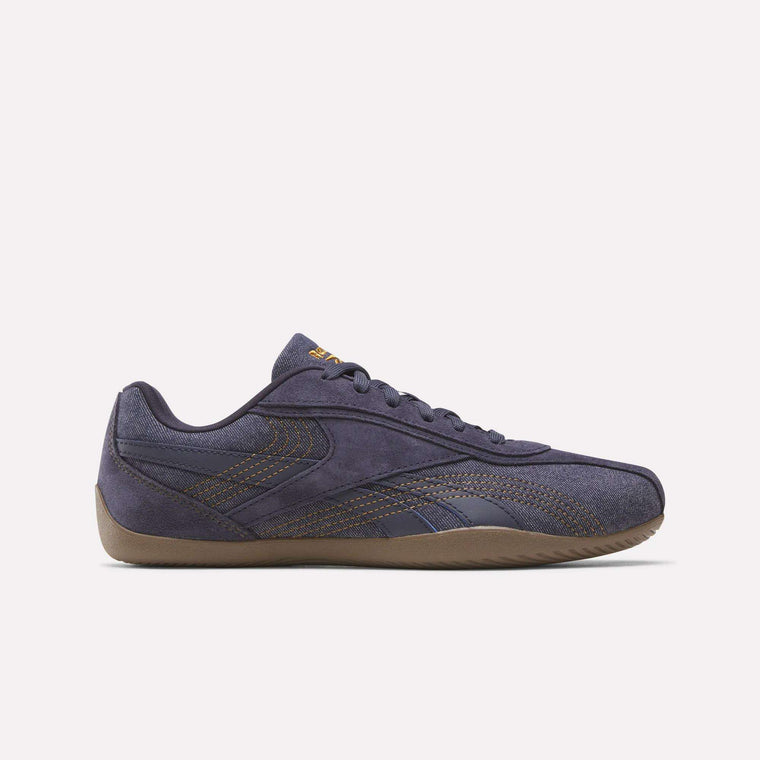 The Women's Ultra Lo Shoes by Reebok in Darkindigo/Reeboklee2 are showcased in side profile against a white background, featuring brown stitching, a gum-colored sole, and a low-top silhouette inspired by Reebok motorsport.