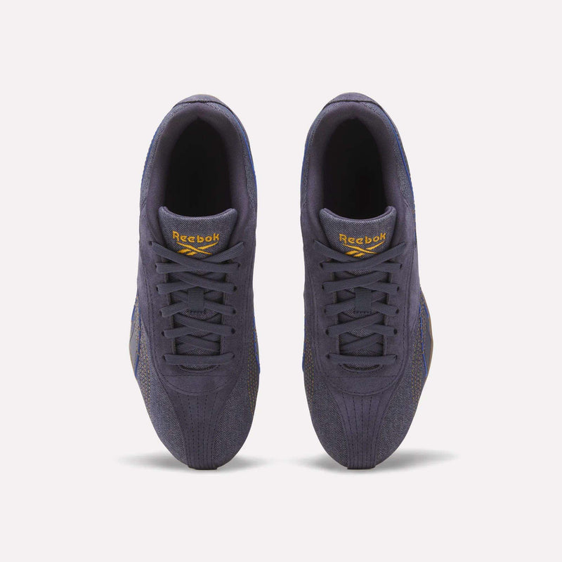 Top view of a pair of Reebok Women's Ultra Lo Shoes in dark purple, featuring yellow Reebok logos on the tongues, set against a white background.