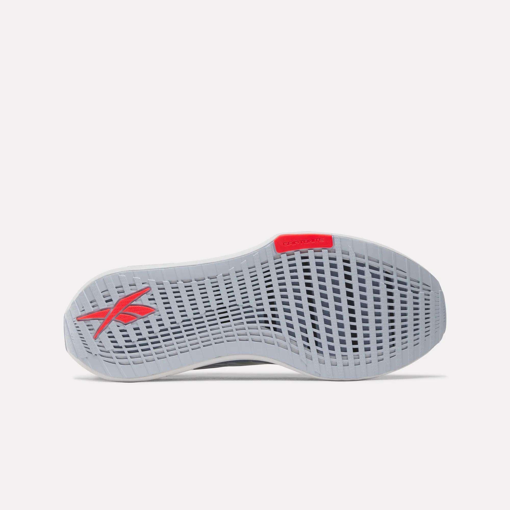 The image shows the sole of the Men's FloatZig Tread Running Shoes by Reebok in light gray, featuring a grid-like tread pattern, a red Reebok logo near the heel, and a red accent at the toe—perfect for treadmill workouts.