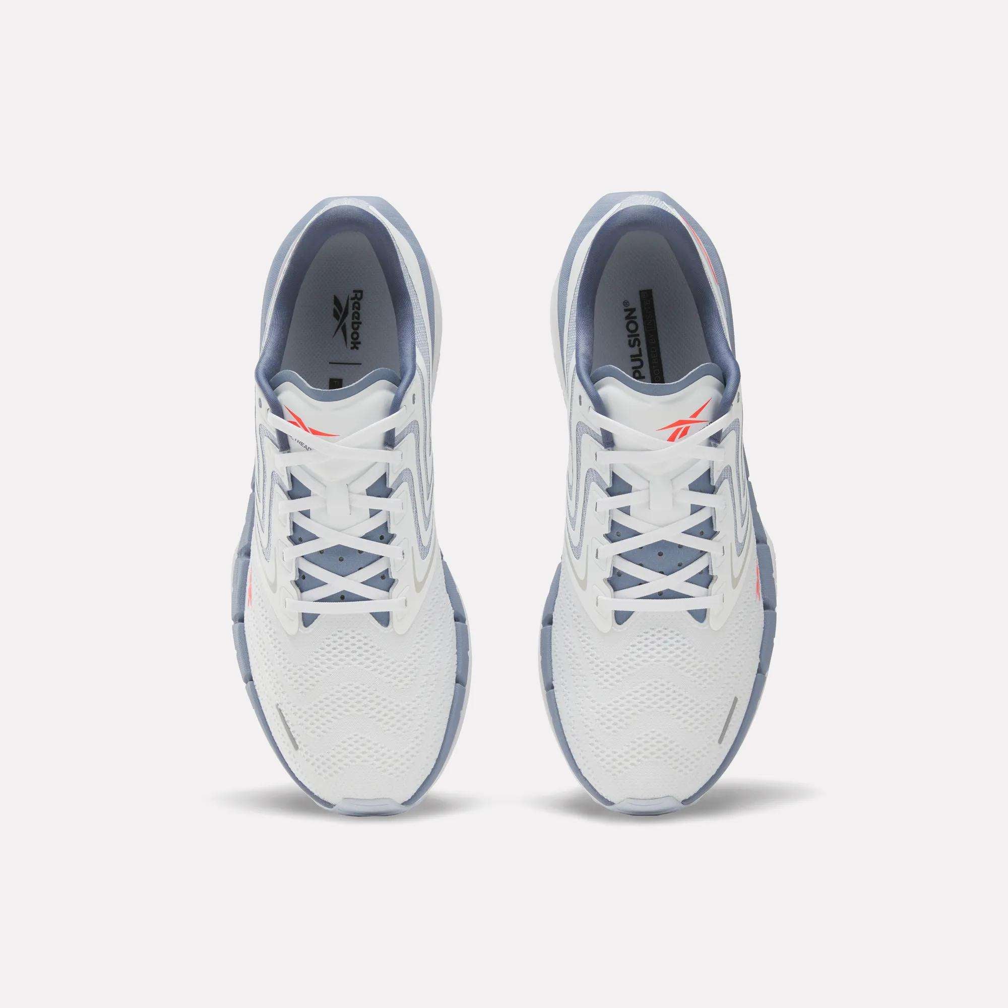 A pair of Reebok Men's FloatZig Tread Running Shoes in white with light blue accents viewed from above, highlighting the laces, mesh upper, and Reebok logo—perfect for treadmill workouts.