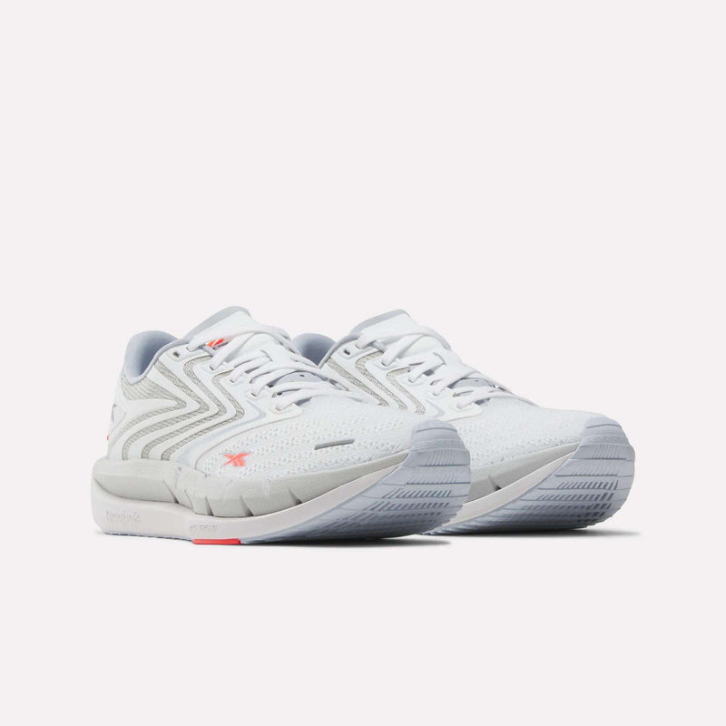 A pair of Reebok Women's FloatZig Tread Running Shoes in white with gray accents, breathable mesh uppers, textured soles, and subtle red logo details are displayed side by side on a plain white background.