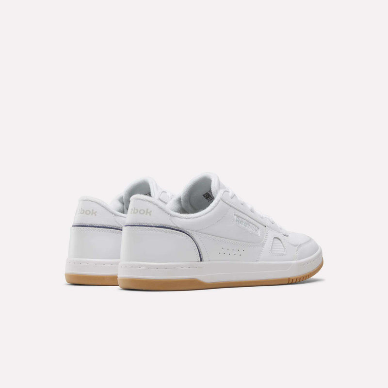 A pair of Men’s Court LXS Shoes by Reebok is displayed at an angle on a plain, light background. Made from premium full grain leather, these white court shoes for men feature gum soles, subtle detailing, and a timeless low-top silhouette.