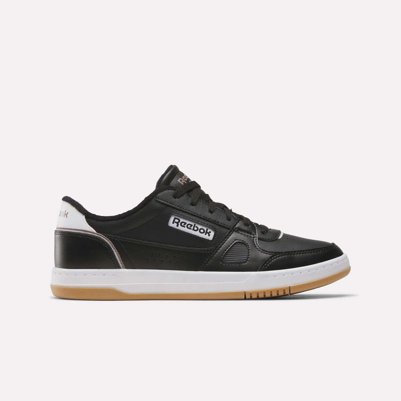 Introducing the Reebok Men’s Court LXS Shoes in Black/White/New Grey 1, expertly crafted from premium full grain leather. This stylish men’s court shoe features a classic white and gum sole, black laces, crisp white detailing around the heel, and a bold white Reebok logo on the side. Set against a plain white background for an elegant presentation.