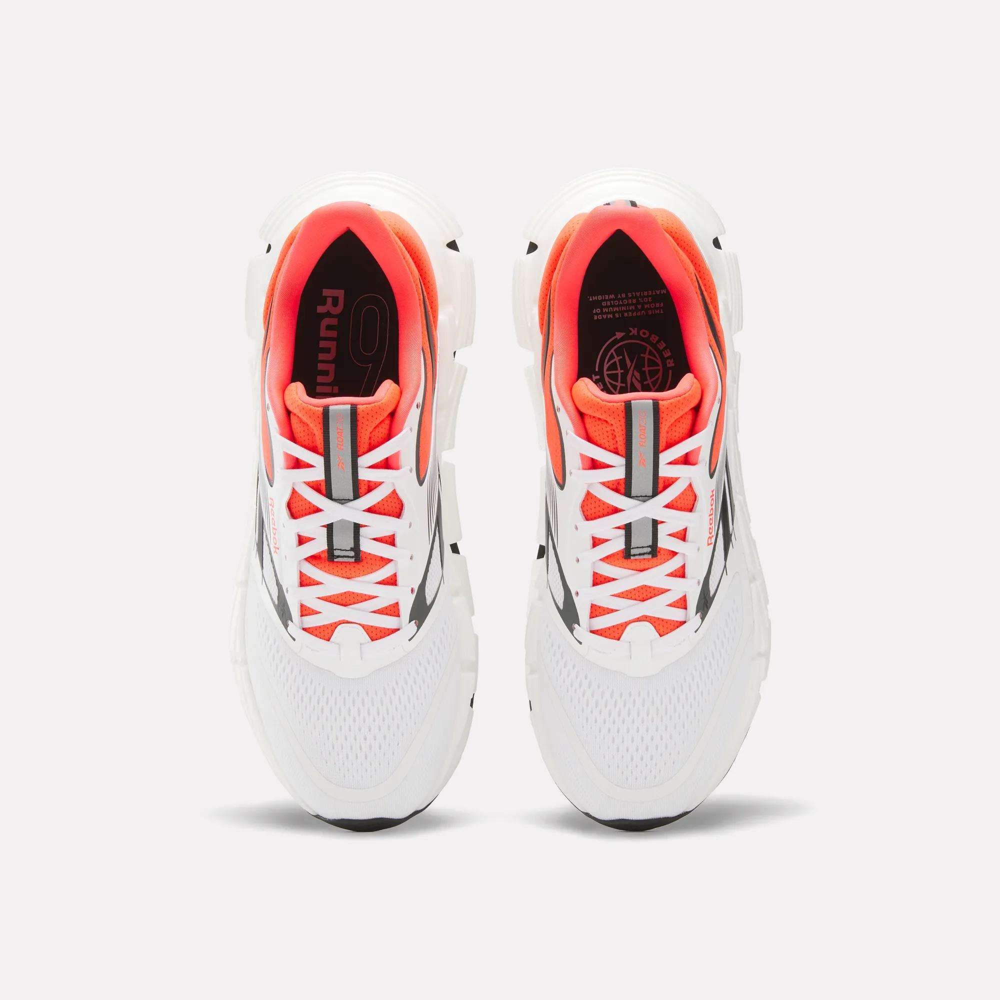A pair of Reebok Men's FloatZig 2 Running Shoes with Superfloat+ cushioning, supportive white upper, orange inner lining, gray accents, and white laces is shown from above on a plain light background.