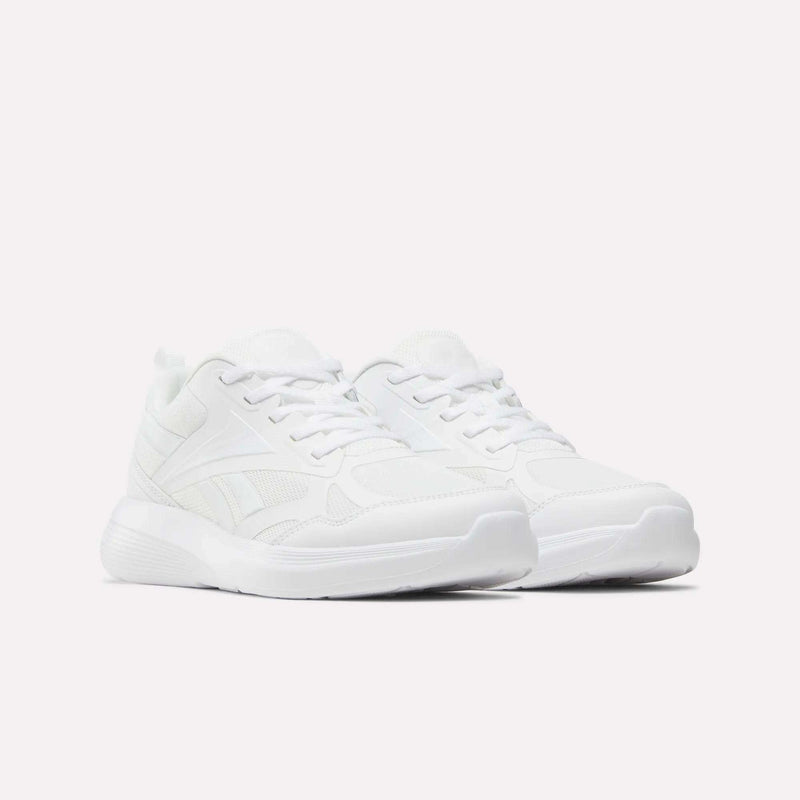 A pair of all-white Reebok Rush Runner 6.0 Running Shoes for big kids, featuring laces, mesh, and synthetic material, displayed on a plain white background.