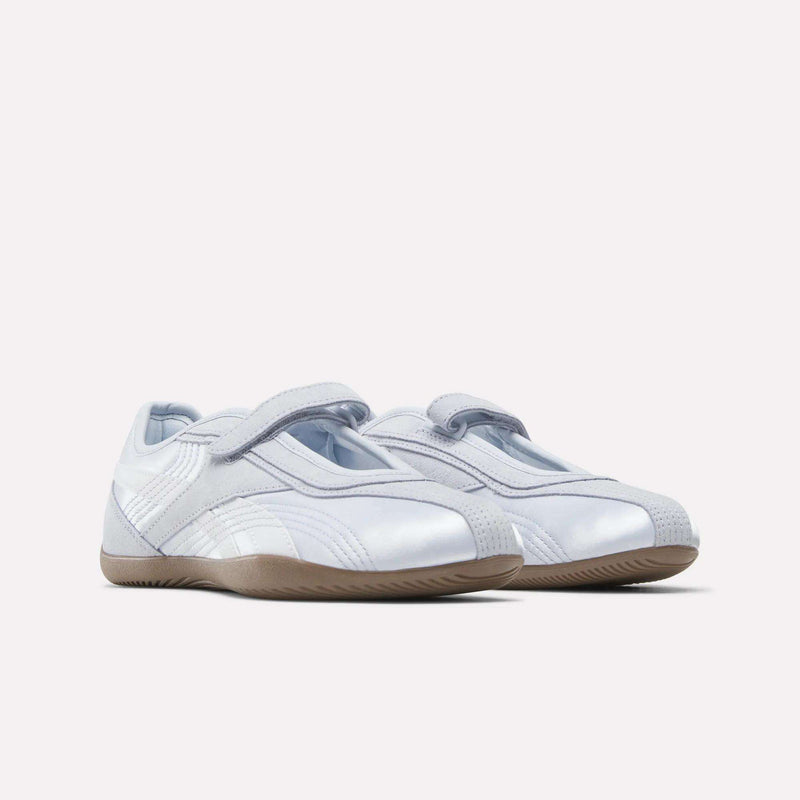 A pair of Reebok Women's Ultra Lo Mary Jane Shoes in sleek white with light gray accents, velcro straps, and gum rubber soles, shown on a plain white background.