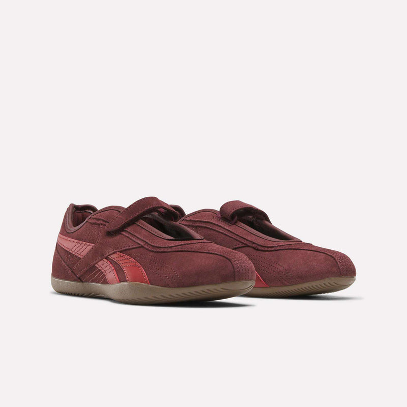 A pair of Women’s Ultra Lo Mary Jane Shoes by Reebok, featuring maroon suede uppers, velcro straps, red accents, and gum rubber soles, displayed on a light background.