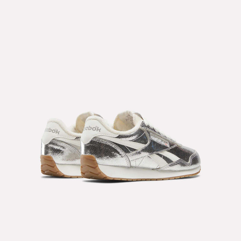 A pair of Reebok Women’s Classic AZ Shoes featuring shiny silver uppers, white accents, beige lining, and brown rubber soles, displayed against a plain white background.