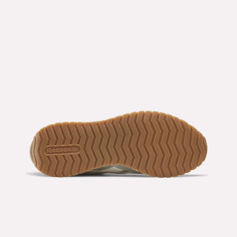 Bottom view of the Women’s Classic AZ Shoes by Reebok, showcasing a textured, light brown rubber sole with zigzag patterns and embossed Reebok branding near the heel. The plain white background accentuates these retro running shoes’ distinctive outsole design.