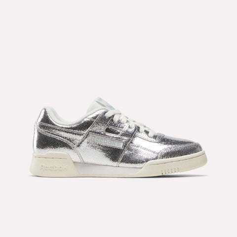 A pair of Reebok Women’s Workout Plus Shoes in Silver Metallic/Chalk/Vintage Chalk, crafted from premium garment leather with matching white laces and chalk-toned sole, shown from a side angle against a plain white background for a classic sneaker aesthetic.