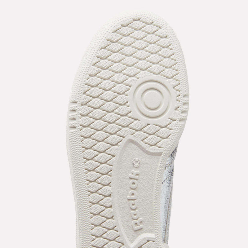 Close-up of a white Women’s Club C 85 Shoe sole by Reebok, tennis-inspired with a textured hexagonal grip pattern, a circular design near the ball, and an embossed Reebok logo.
