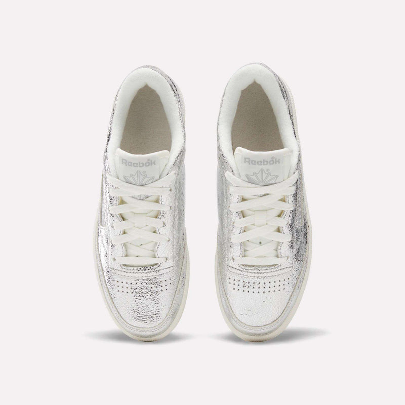 A pair of Reebok Women’s Club C 85 Shoes in metallic silver leather with white laces, photographed from above against a plain light background.
