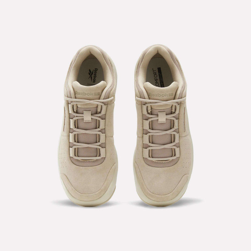 A pair of beige Reebok DMX Comfort+ Classic sneakers viewed from above, crafted from premium leather and featuring laces, perforated toes, and Reebok logos on the insoles.
