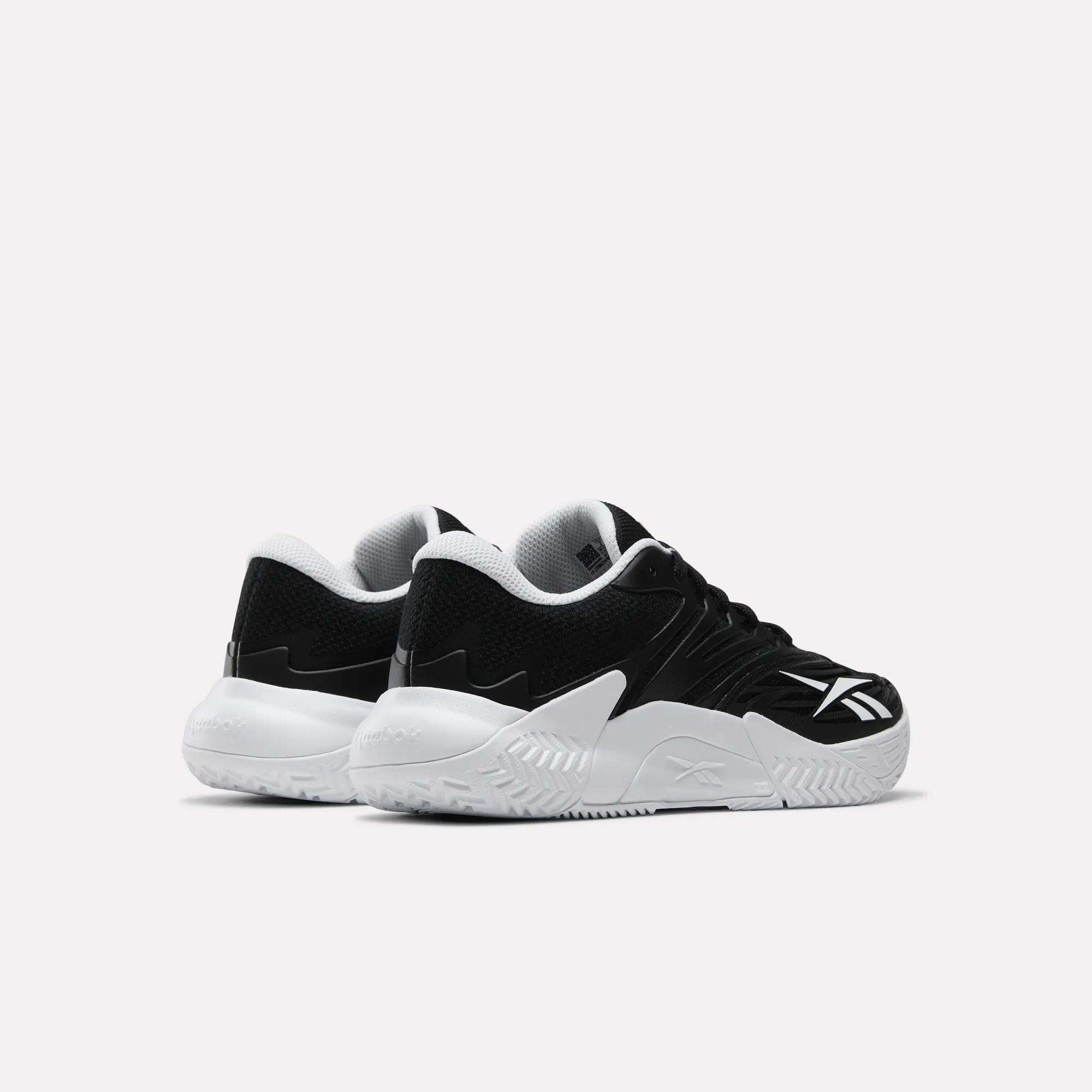 The Women's Phase Evo Tennis Shoes by Reebok in black and white, featuring thick white soles and shown from the back and side on a light background—durable footwear blending style and performance.