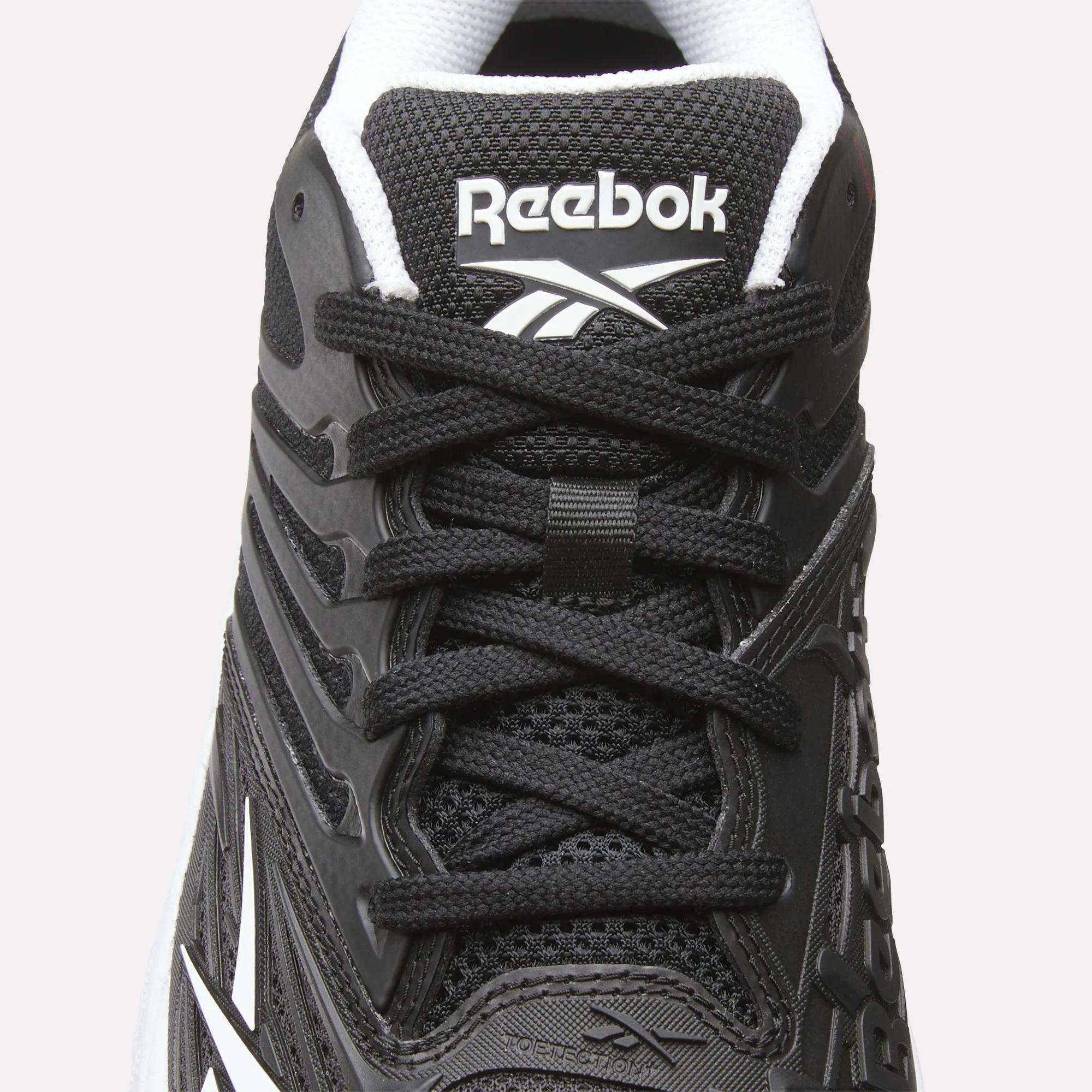 Close-up of the Women's Phase Evo Tennis Shoes by Reebok in black with white accents, featuring laces, mesh texture, side design, and the Reebok logo on the tongue.