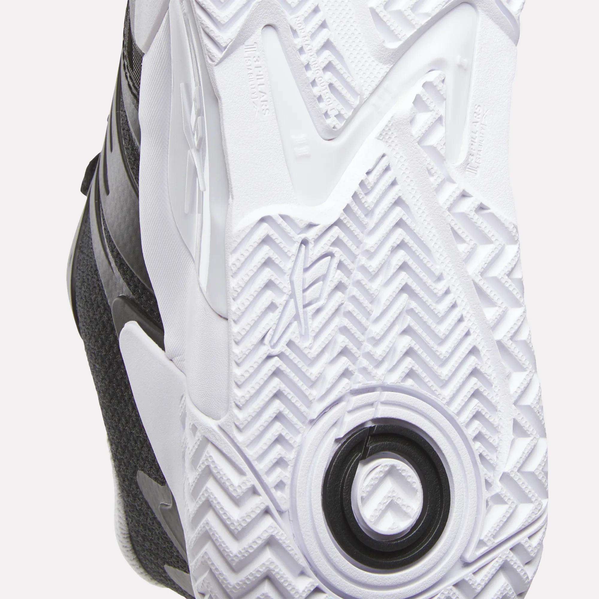Close-up of the white rubber outsole on Reebok Women's Phase Evo Tennis Shoes, featuring a herringbone tread, circular heel detail, and textured grip for traction and support—ideal for long-lasting tennis performance.