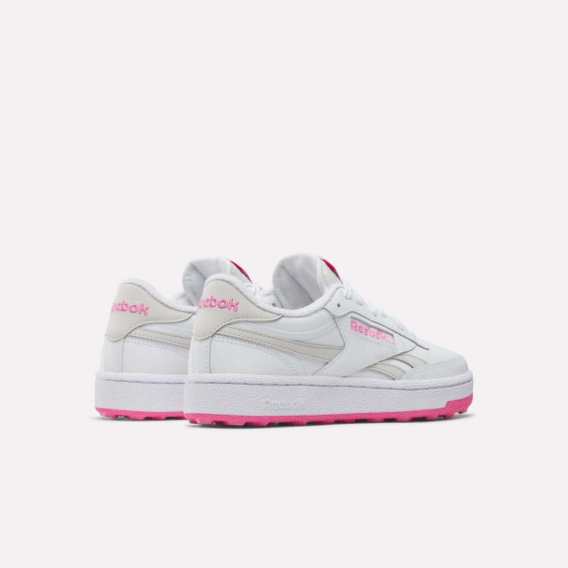 Two white Reebok Women’s Club C Revenge Golf Shoes with pink soles and pink Reebok logos are displayed from a rear side angle on a plain white background—these women’s golf shoes blend style and comfort in a spikeless design, making them ideal for both on and off the course.