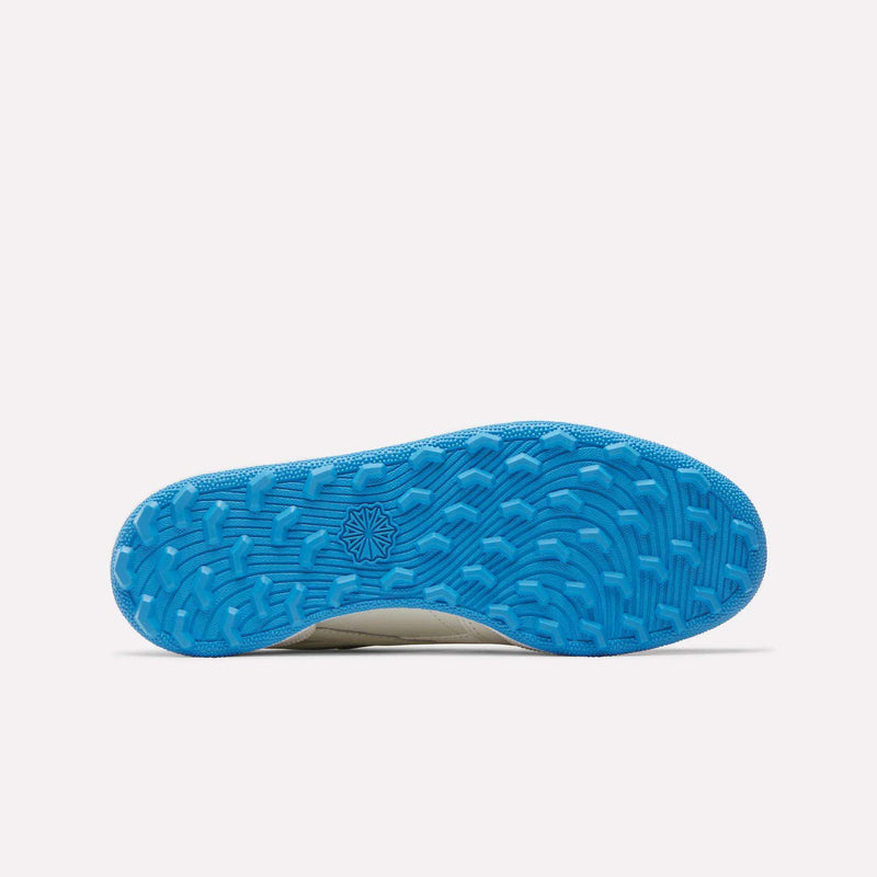 The image displays the bottom view of the Reebok Women’s Club C Revenge Golf Shoes, featuring a bright blue spikeless sole with a textured, wavy tread pattern and a geometric star-shaped logo in the center. The background is plain white.