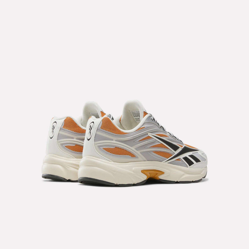 A pair of Reebok Premier Road 1000 Shoes in white with orange and gray accents, black detailing, and thick soles with an EVA midsole, displayed on a plain white background.