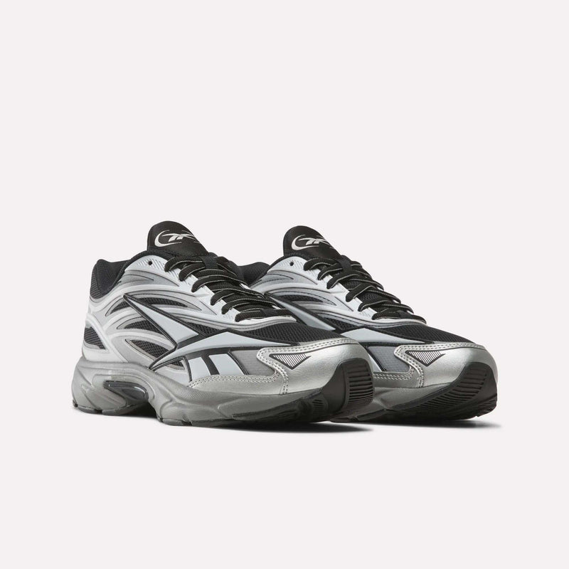 A pair of Reebok Premier Road 1000 Shoes in silver and black, featuring chunky soles, mesh paneling, and striking dynamic accents, are displayed side by side on a clean white background. These retro runners embody classic Y2K sneaker style for a bold statement look.