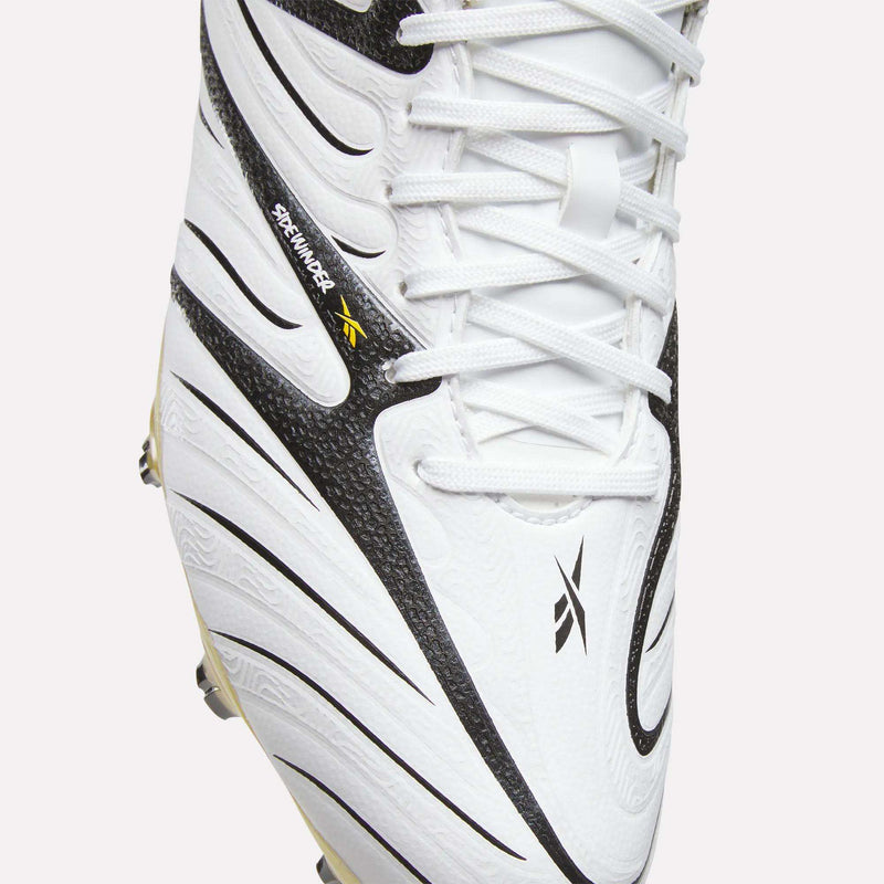 Close-up of the Reebok Sidewinder 26 Pro Firm Ground Cleats in white, showcasing black curved patterns, white laces, and a small black and yellow Reebok logo. Engineered for firm ground play, these cleats feature textured detailing and visible stitching to improve ball control.