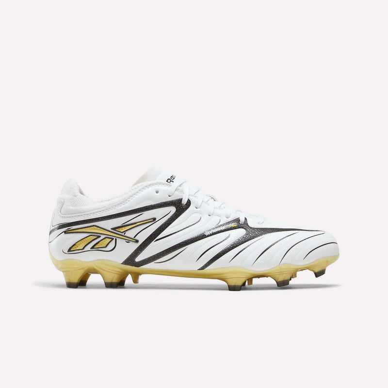 The Reebok Sidewinder 26 Pro Firm Ground Cleats are shown in profile on a plain background. Featuring a white upper with black and silver accents, these cleats include the signature Reebok logo in black and silver, a lace-up closure, and molded studs on the sole designed for enhanced ball control.