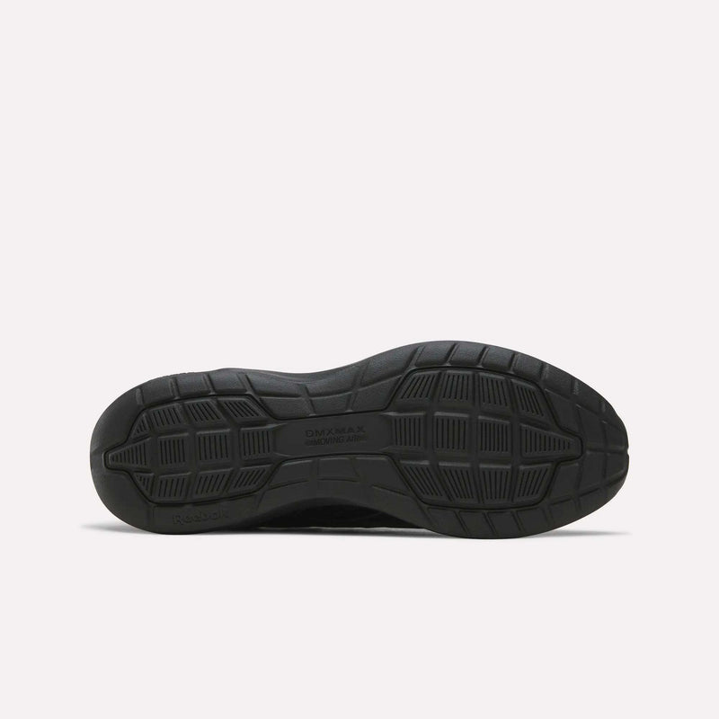 The image displays the black rubber sole of the Reebok Men's Walk Ultra 7 DMX Max Shoes, positioned flat to showcase its tread pattern. The sole includes textured grip sections and features DMX MAX and Reebok embossed on it, emphasizing the advanced DMX cushioning technology characteristic of these cushioned walking shoes.