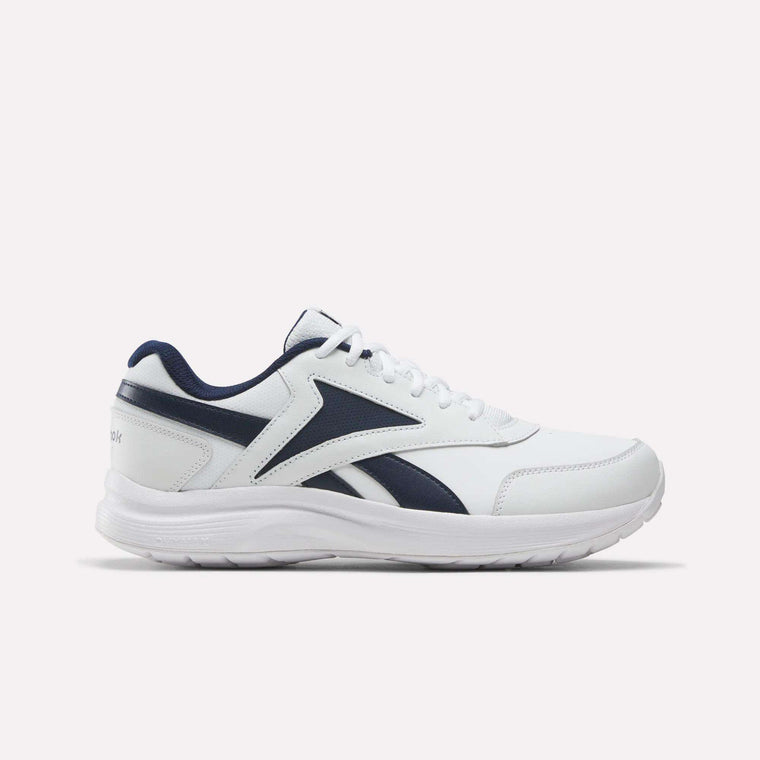 A pair of Reebok Men's Walk Ultra 7 DMX Max Shoes - Wide 4E in White/Collegiate Navy/Collegiate Royal, featuring white athletic uppers accented with navy blue and royal geometric designs on the side, white laces, and a matching white sole. Shown in a side profile on a plain background, these men's sneakers offer DMX cushioning for enhanced comfort and support throughout the day.