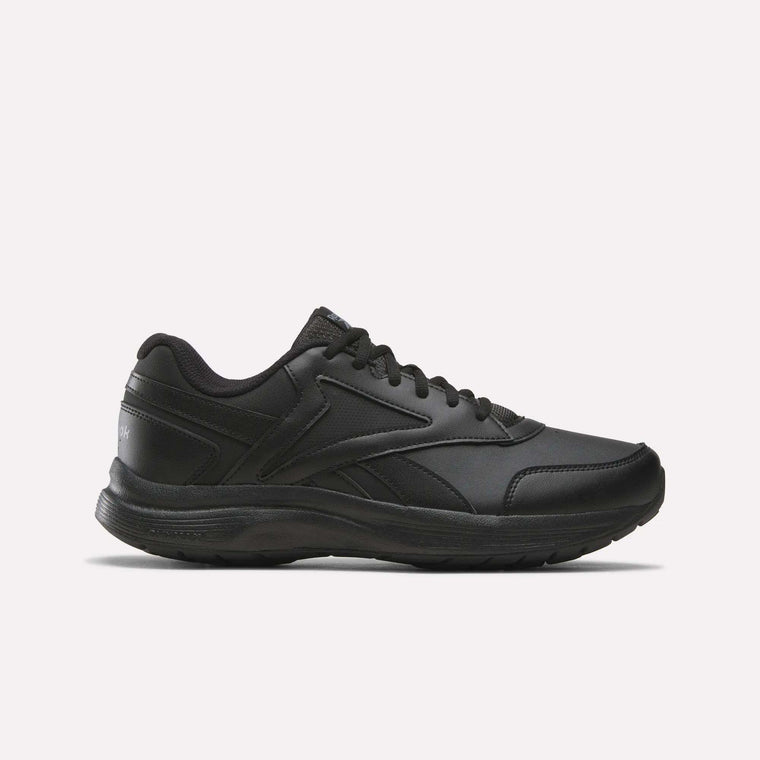 A side view of the Reebok Men's Walk Ultra 7 DMX Max Shoes - Wide 4E in Black/Cold Grey 5/Collegiate Royal is displayed on a plain white background, showcasing its lace-up design, low-cut profile, and textured sole with DMX cushioning for enhanced comfort.