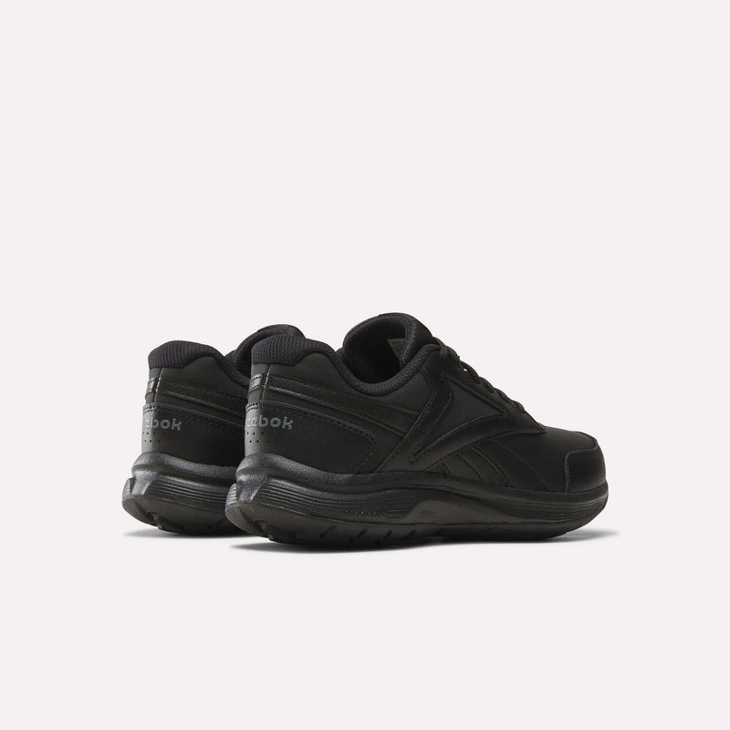 A pair of Women’s Walk Ultra 7 DMX Max Shoes by Reebok, shown from the back and side, featuring a black low-top design with a lace-up closure and subtle Reebok branding on the heel and side. Designed as cushioned walking shoes for all-day comfort, they are positioned on a plain white background.