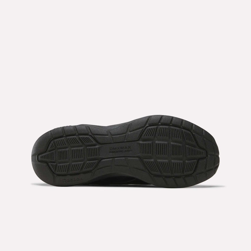 The image displays the black rubber outsole of a Reebok Women’s Walk Ultra 7 DMX Max Shoes - Wide D, seen from the bottom. The sole features textured patterns and grooves for traction, with “DMX MAX” and “MOVING AIR” inscribed to emphasize comfort-focused technology designed for all-day wear.