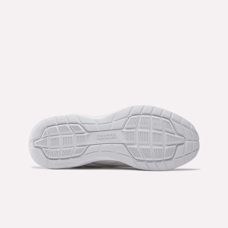 The image displays the bottom view of a white Women’s Walk Ultra 7 DMX Max Shoes - Wide D by Reebok, highlighting the textured outsole patterns and the “DMX MAX MOVING AIR” text that signifies the advanced cushioning technology engineered for all-day comfort in these Reebok walking shoes.