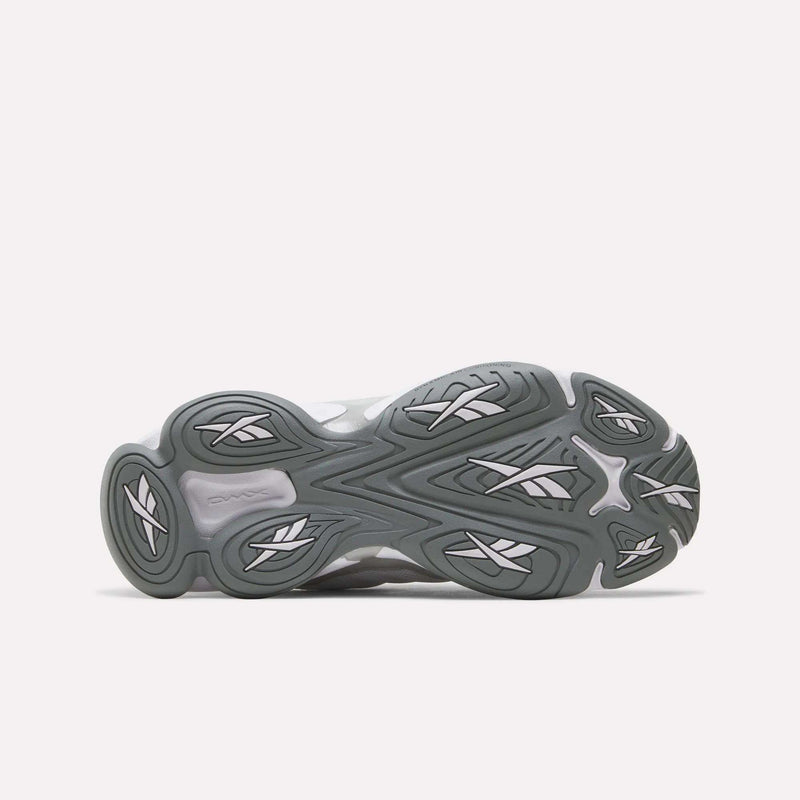 The bottom view shows the gray rubber outsole of the Reebok Women’s DMX Series 3000 Shoes, featuring a wavy, sculpted tread pattern with white accents against a plain light background. This lightweight sole highlights Reebok’s advanced DMX moving air technology, renowned for delivering ultra-cushioned comfort.