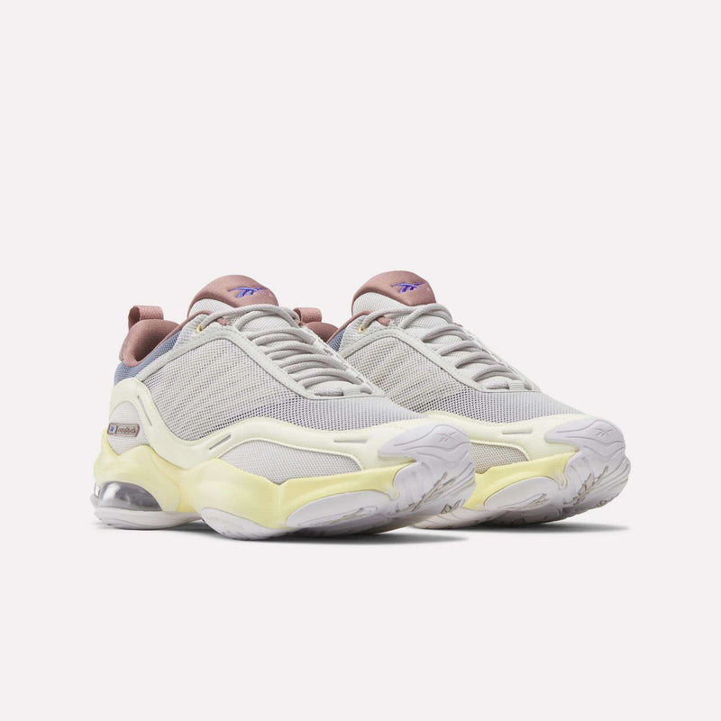 The Reebok Women's DMX Series 3000 Training Shoes feature white mesh uppers with pale yellow and lavender accents, chunky soles, and visible air cushioning enhanced by DMX 3 Technology, displayed against a plain white background.