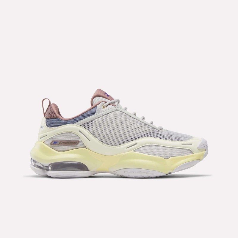 Introducing the Reebok Women's DMX Series 3000 Training Shoes—a stylish athletic shoe featuring a cream-toned New Grey mesh upper accented with Raw Yellow and Hazy Blue details. Designed with layered textures, a translucent sole, and a chunky silhouette, these shoes combine modern aesthetics with the signature cushioned comfort of Reebok walking shoes.