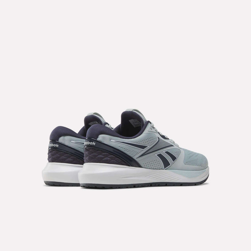 A pair of Reebok Women’s NFX Trainer 2 Training Shoes in gray and navy is displayed on a white background, angled to showcase the back and side details of both shoes.