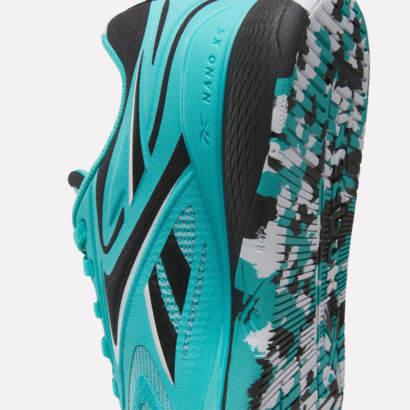 A close-up of the Reebok Women’s Nano X5 Edge Training Shoe in turquoise, featuring black accents and a patterned sole in black, white, and turquoise. This athletic shoe is designed with mesh fabric and a textured tread, making it perfect for training sessions.