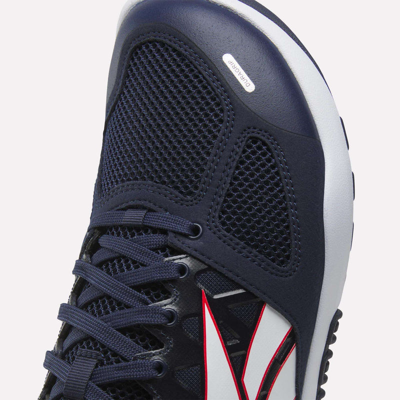 Close-up of the Reebok Men’s Nano 2.0 Training Shoe in navy blue, featuring black mesh construction, dark blue laces, and a white midsole. The shoe is accented with a distinctive white and red side design and has an Ortholite label near the toe. Engineered by Reebok for functional fitness, these training shoes combine comfort and durability to deliver optimal performance.