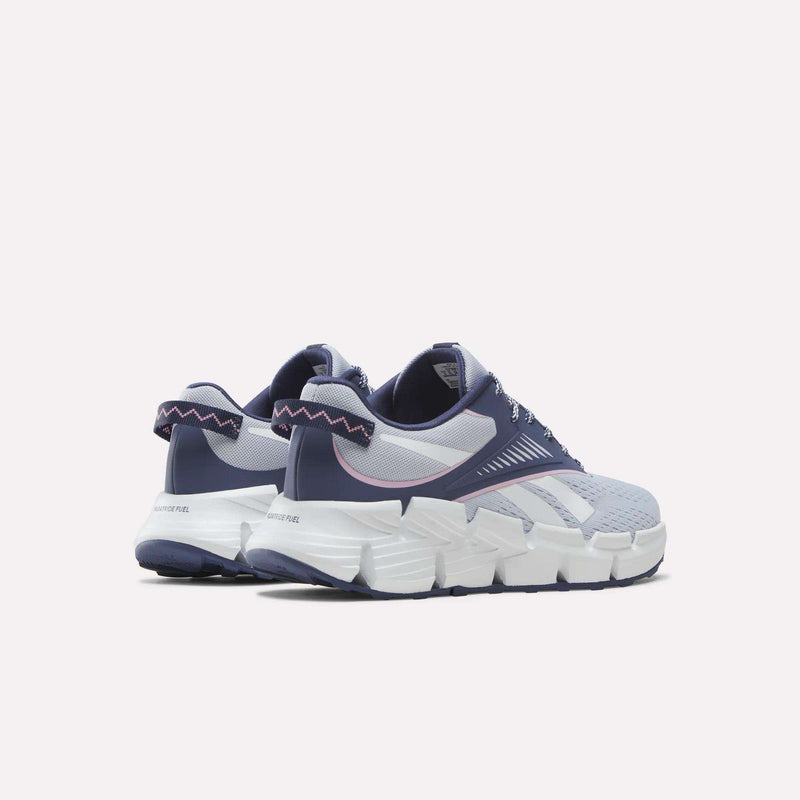 A pair of Reebok Zig Dynamica 6 Running Shoes for Big Kids in blue, white, and purple feature chunky soles with innovative Zig technology, breathable mesh uppers, and zigzag stitching on the heel—shown against a plain light background.