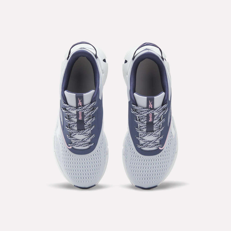 Top view of a pair of Reebok Zig Dynamica 6 Running Shoes for big kids in blue and white, featuring patterned laces, mesh uppers with Zig technology, and dark blue interiors, placed side by side on a light background.