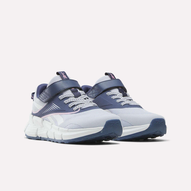 A pair of Reebok Zig Dynamica 6 Shoes for little kids, featuring white and navy blue mesh uppers, thick soles, and both laces and a velcro strap across the top, displayed on a light background.