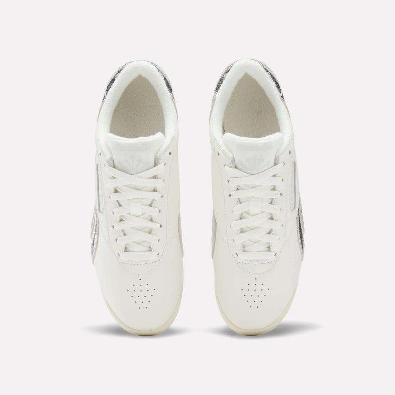 Top view of Reebok Women's Freestyle Lo Shoes with laces and subtle metallic accents on the sides and heel, displayed against a simple light background.