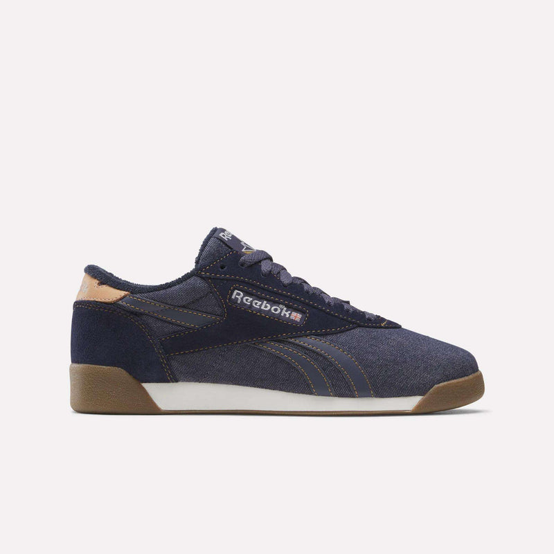 Darkindigo/Chalk/Gum Women’s Freestyle Lo Shoes by Reebok, featuring beige accents, a white midsole, and a brown outsole. These sneakers showcase the iconic Reebok logo on the side and dark laces, photographed against a plain light background—an excellent pick for fans of vintage denim-inspired footwear.
